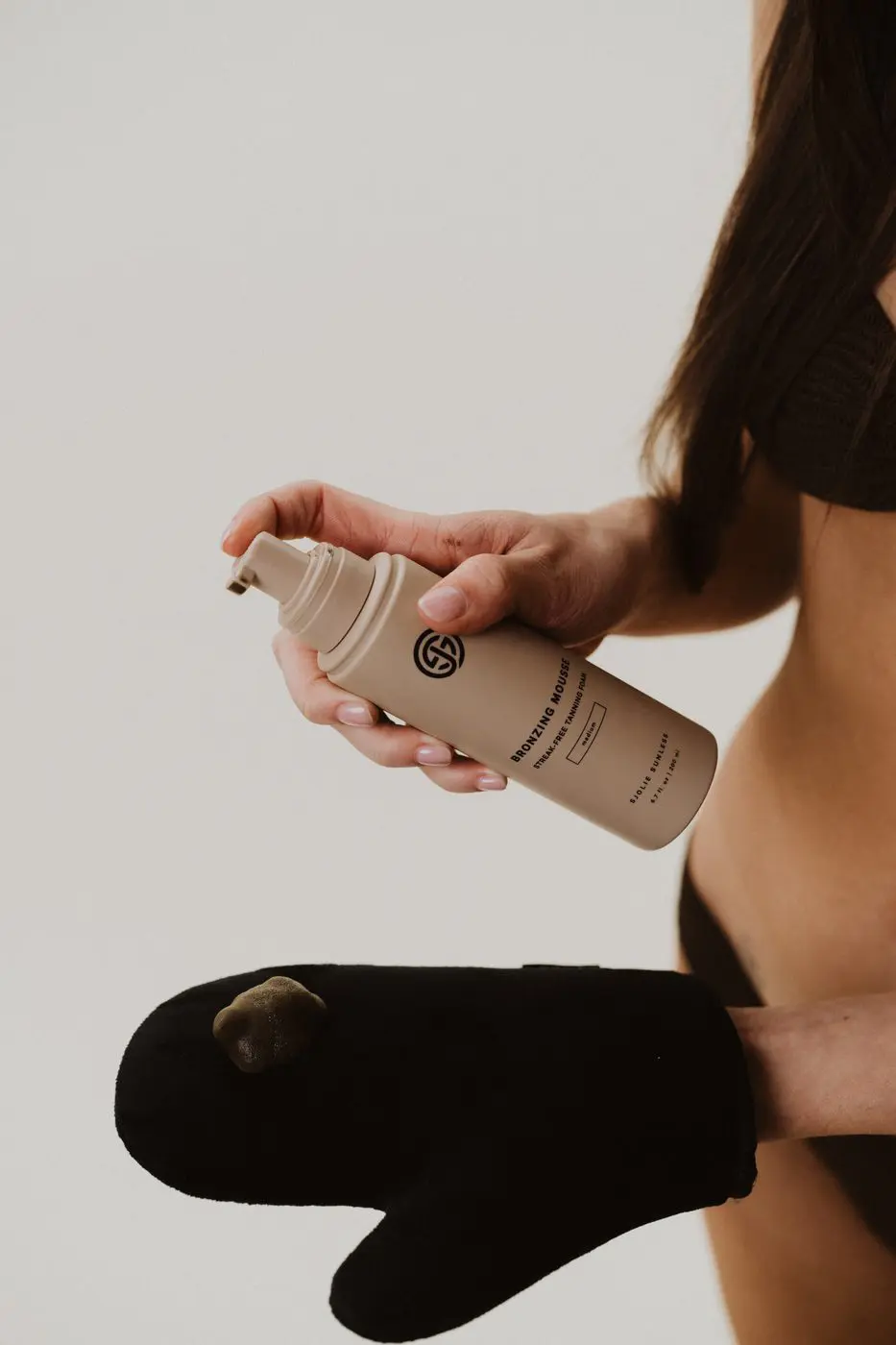 Model using Sjolie Applicator Mitt to apply Bronzing Mousse for even self-tan coverage