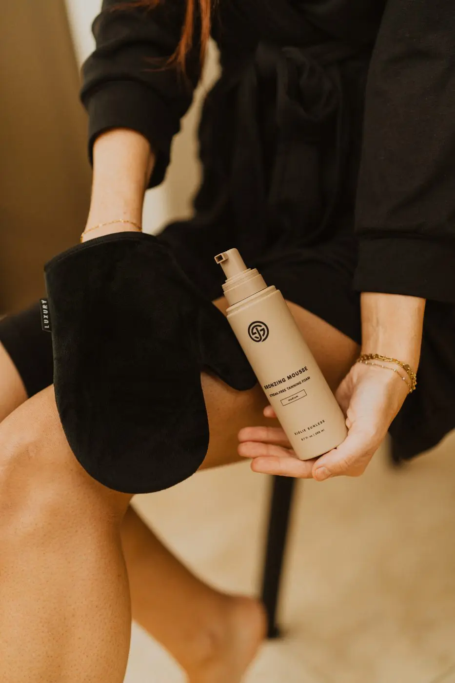 Model applying self-tanner to legs with Sjolie Applicator Mitt for flawless blending