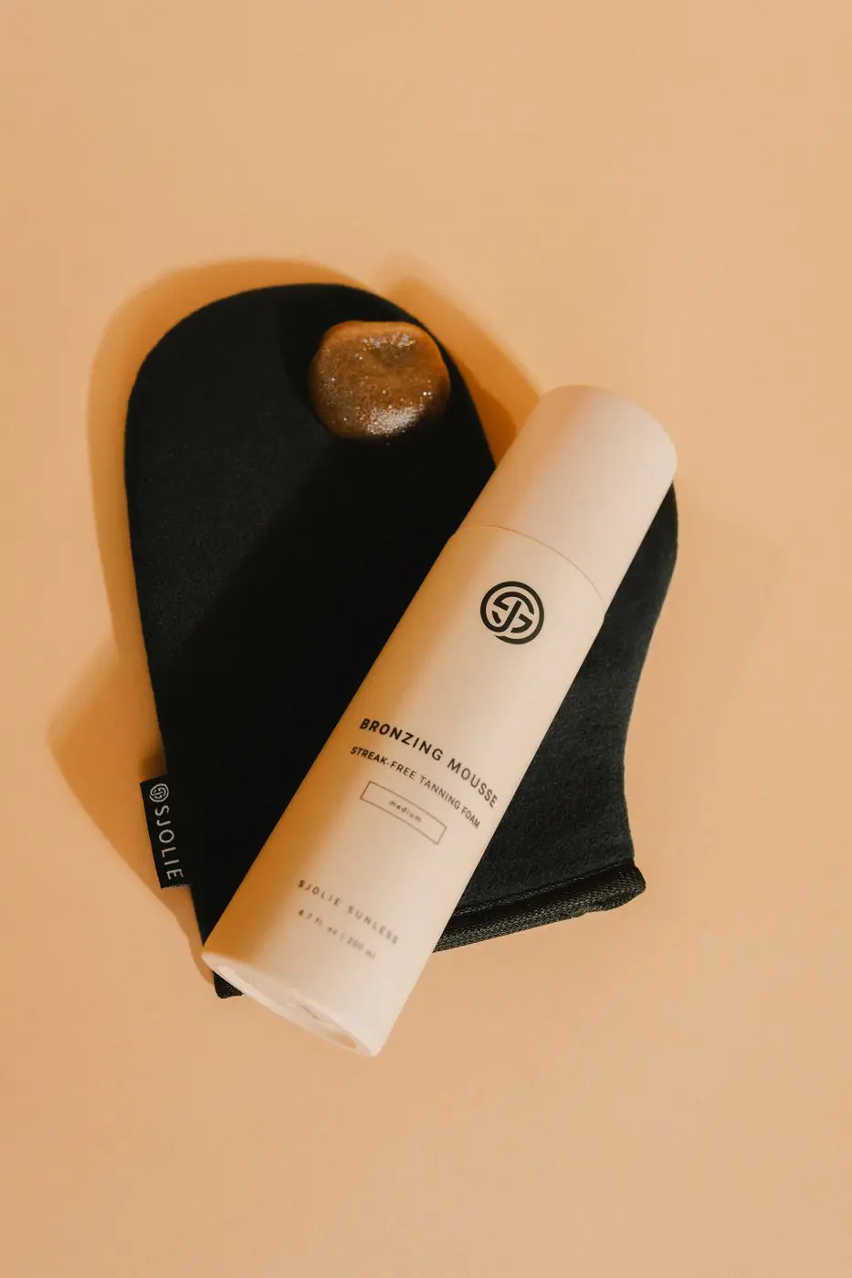 Sjolie Bronzing Mousse self-tanning foam applied with applicator mitt for streak-free at-home tan