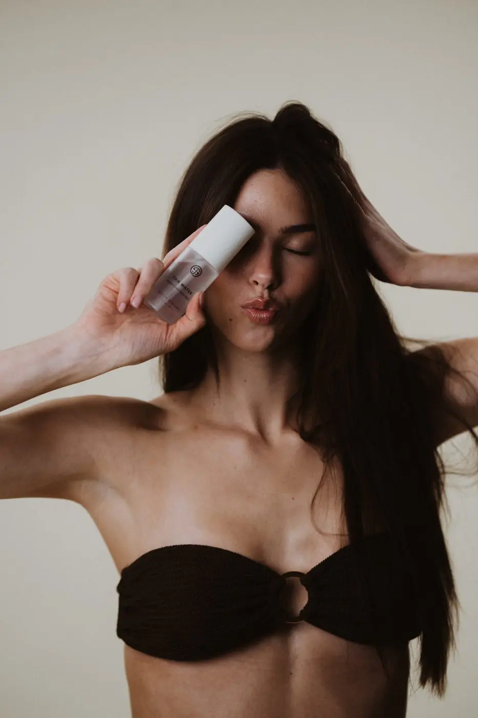 Model holding Sjolie Tan Water hydrating face mist for buildable self-tan color