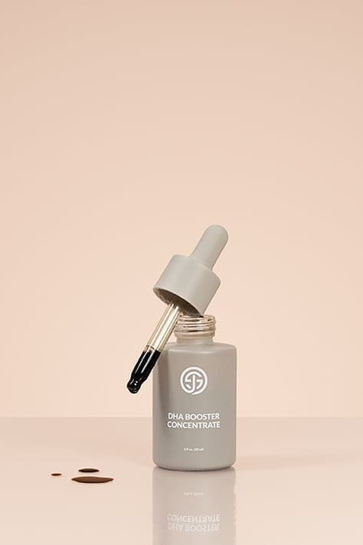 Dropper lifted from an open bottle of SJOLIE DHA Booster Concentrate, drops on the surface