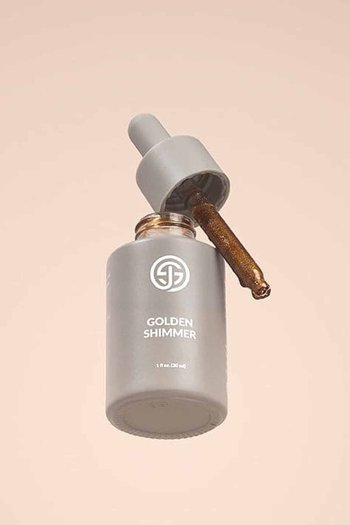 SJOLIE Golden Shimmer Drops bottle floating with its dropper on a peach background