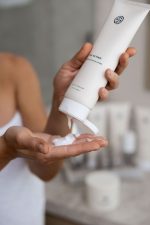 Squeezing SJOLIE Tan Extend Lotion from the tube into an open palm