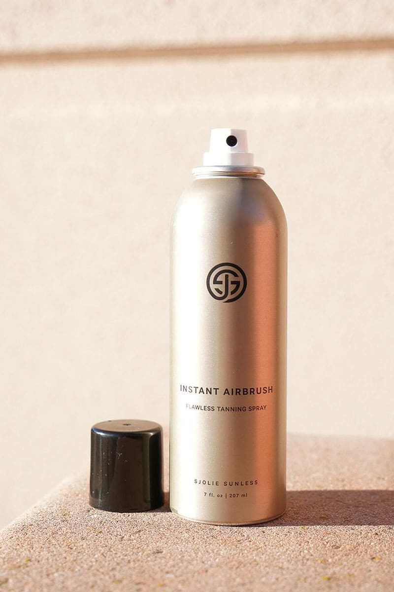 SJOLIE Instant Airbrush tanning spray can with its cap off on a stone block