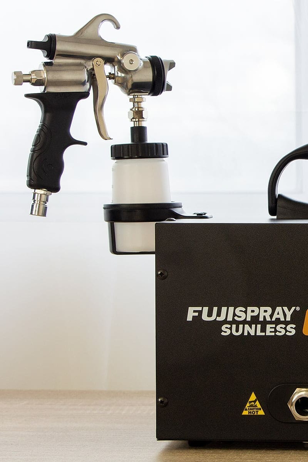 Fuji salonTAN spray tan machine with its applicator gun in the cup holder