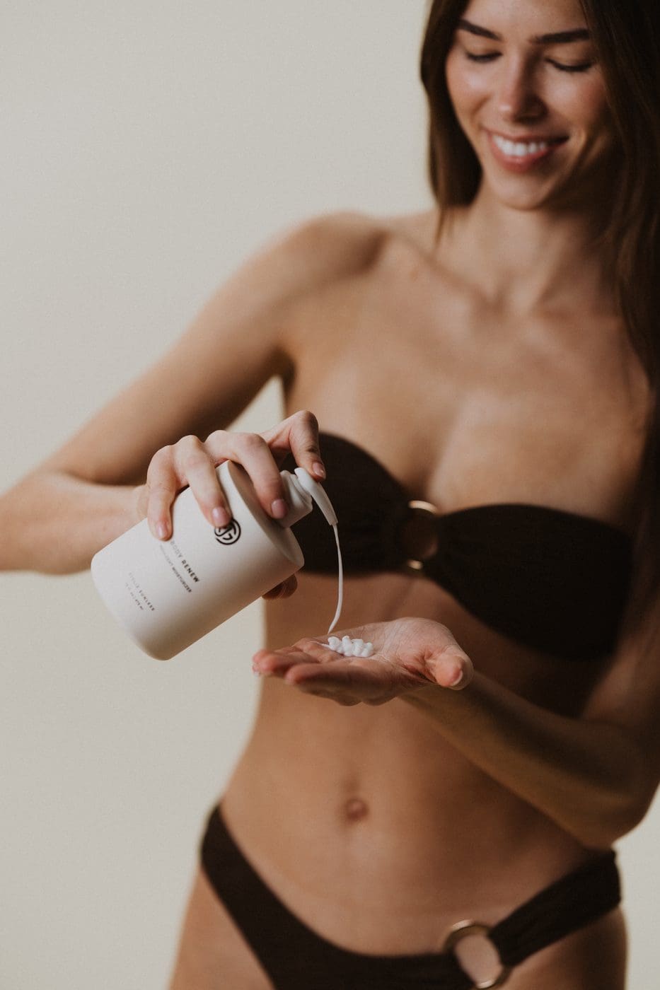 Model pouring Sjolie Body Renew Moisturizer into hand for daily application