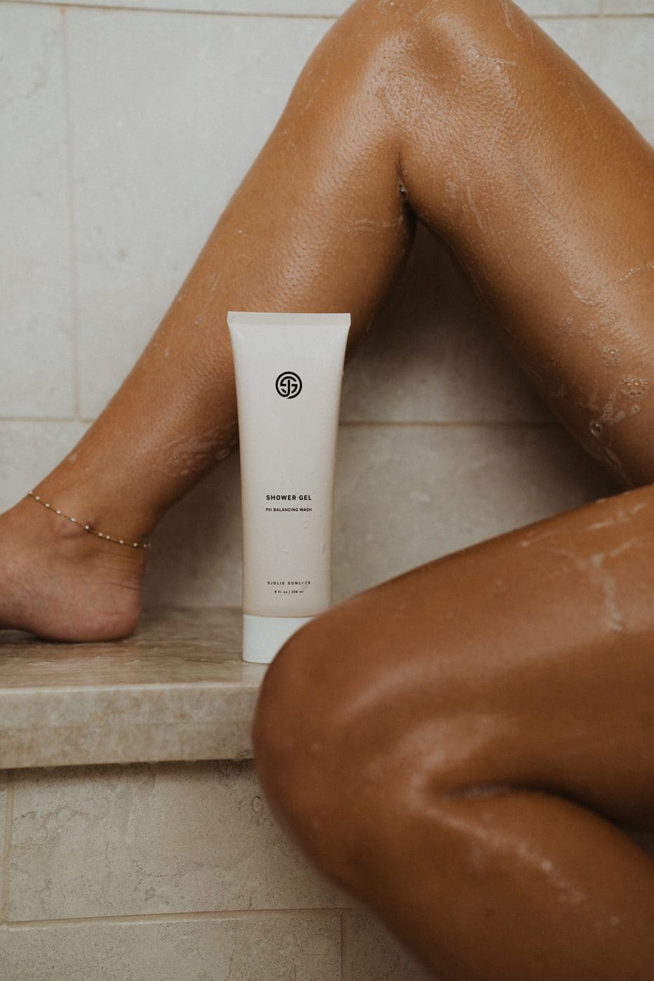 Model using Sjolie Shower Gel pH-balanced body wash to cleanse and preserve spray tan