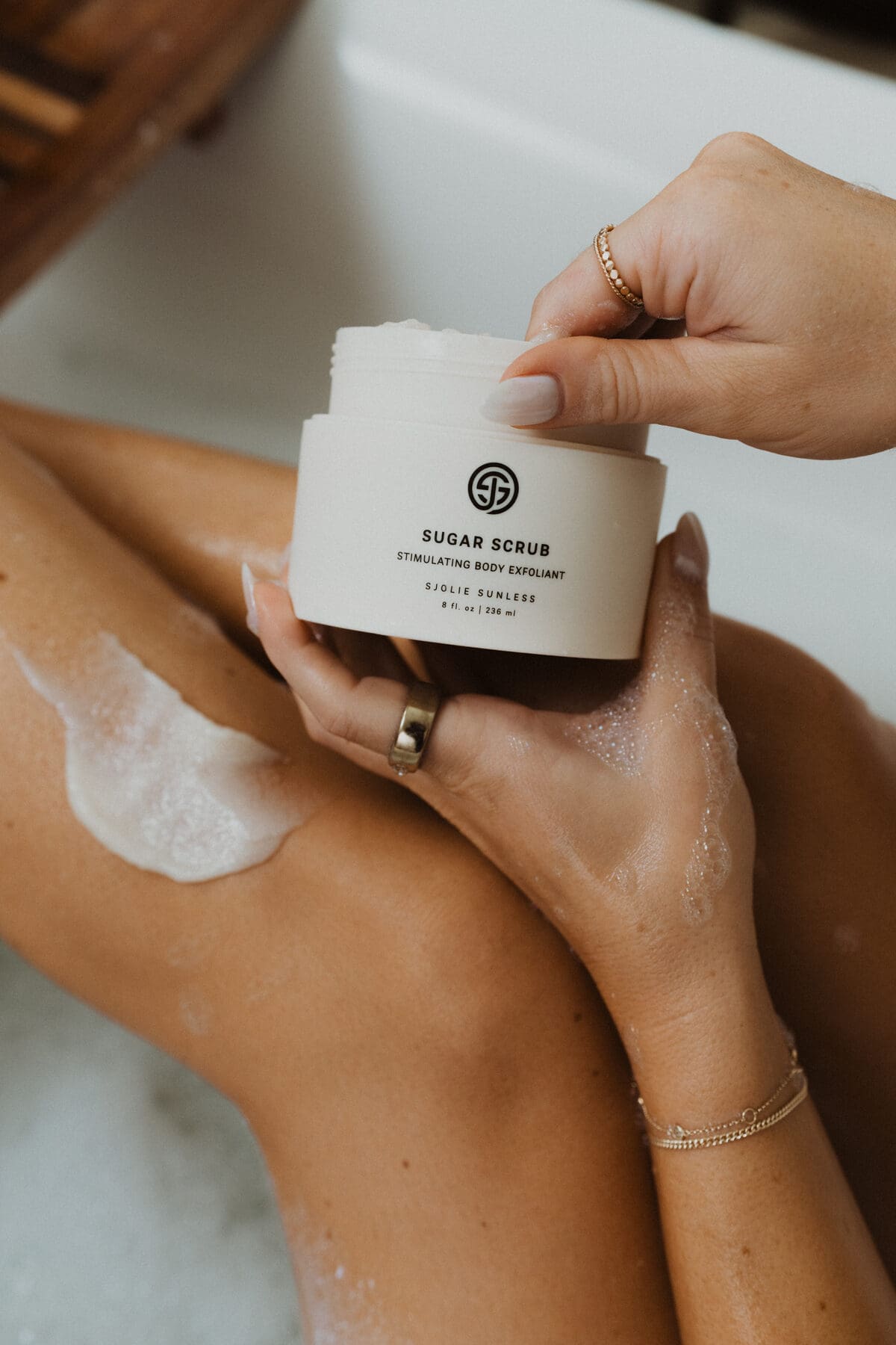 Model applying Sjolie Sugar Scrub oil-free body exfoliant for spray tan prep and removal