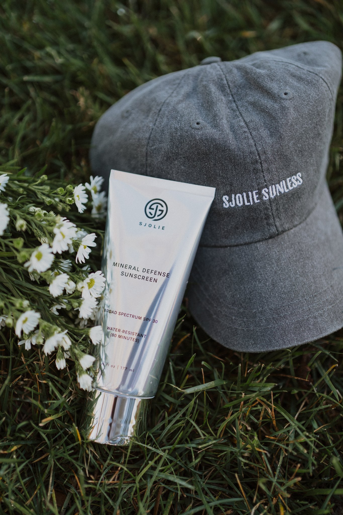 Two friends and a dog on a porch with one holding a Sjolie Mineral Defense Sunscreen tube