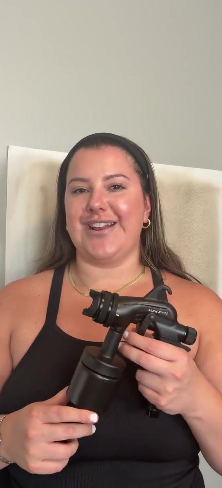 Brielle Camiolo of Deity Mobile Spray Tans holding the Sjolie X1 Pro spray tan applicator
