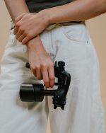 Compact handheld Sjolie X1 Pro spray tan machine shown in hand for scale